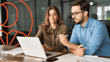man and woman look at a laptop, icon in background