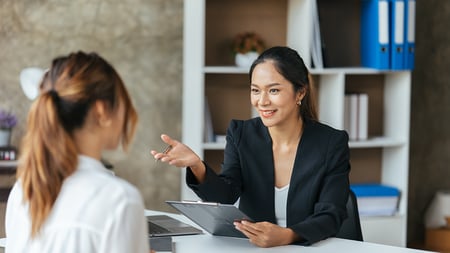 woman speaking to another woman with a tablet in hand 