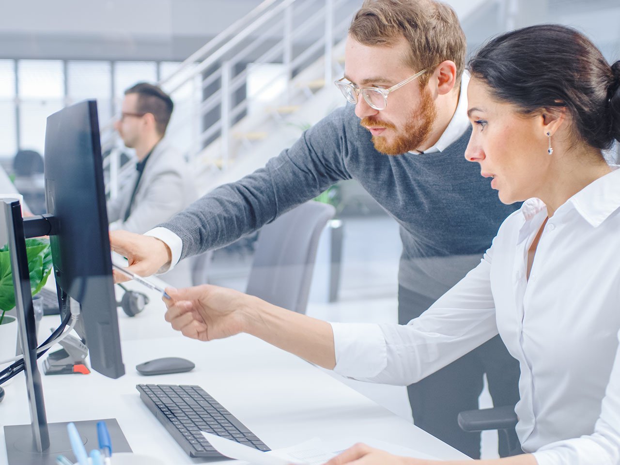 Businesswoman Uses Desktop Computer, Consults Her Project Manager about Documents with Graphs and Statistics.
