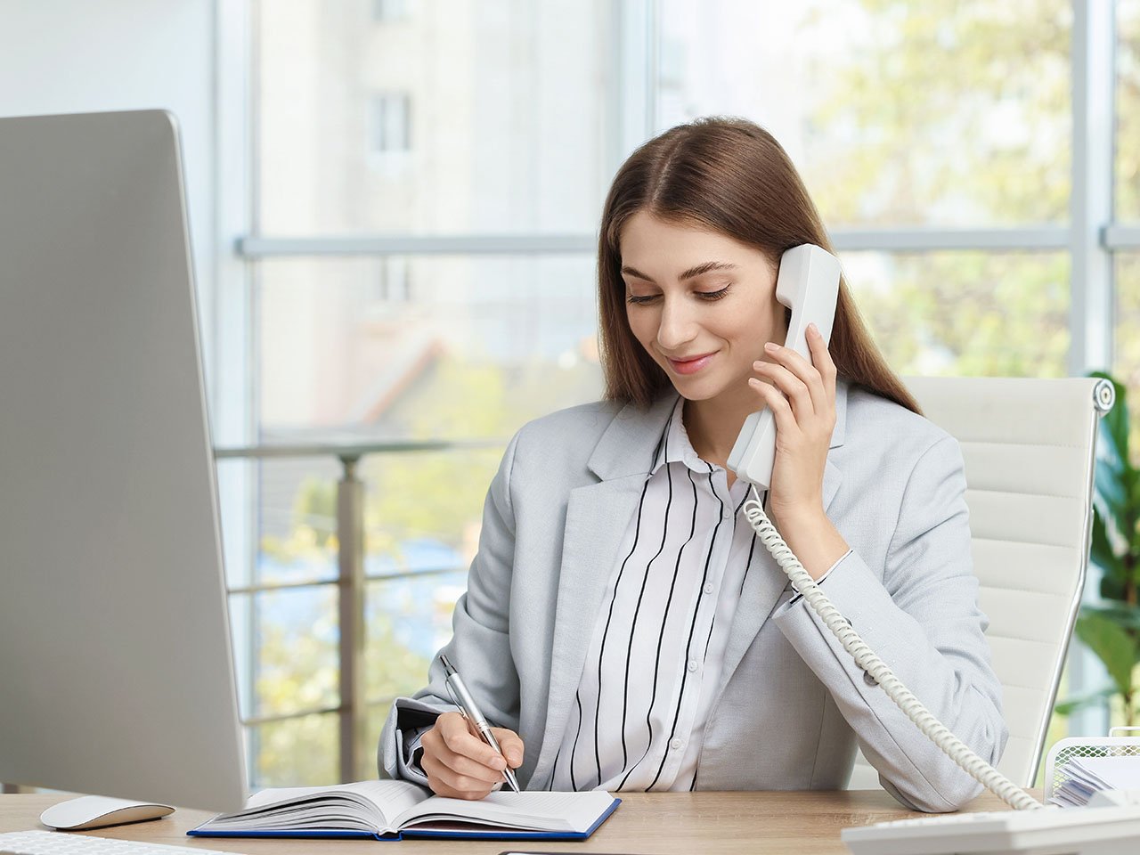 Banker talking on telephone at table in office.